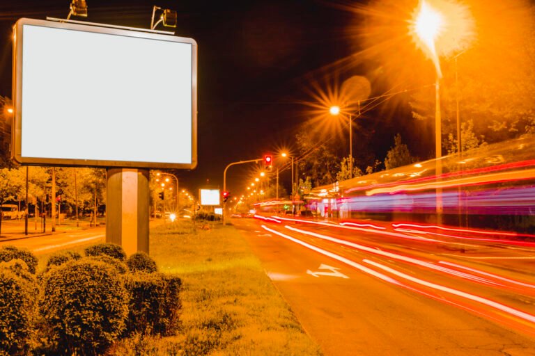 white-blank-billboard-near-roadside-with-rush-hour-traffic-light-trails